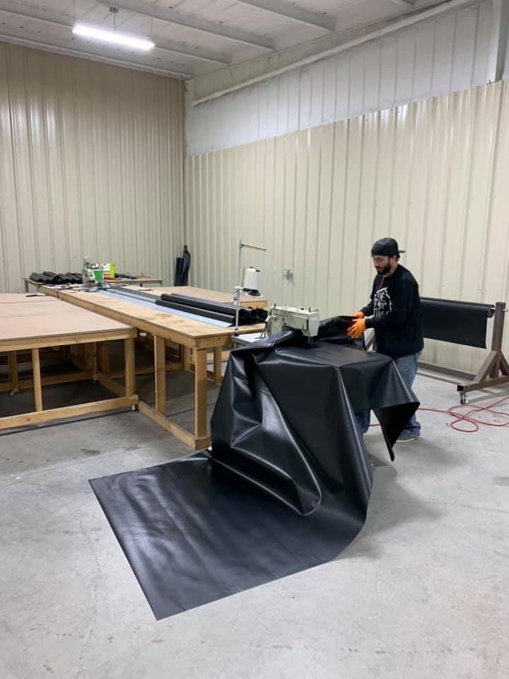 The Tarp House team hand-sewing a custom tarp in the shop